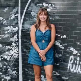 Rilie Tané standing in front of one of her murals
